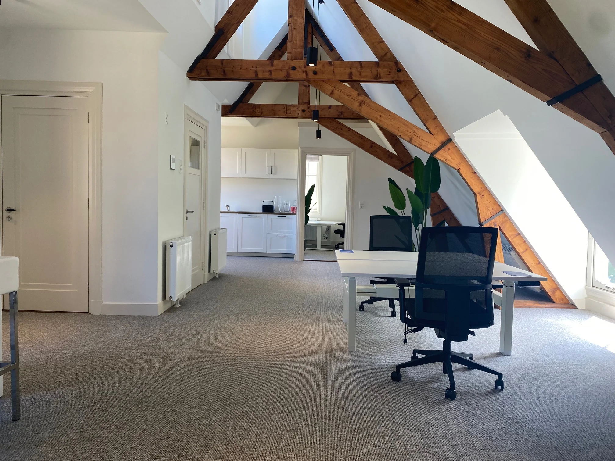Modern kantoorinterieur aan de Kleine Houtweg met zichtbare houten balken, bureaus en een kitchenette.